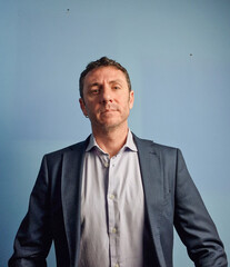 Italian man wearing a smart jacket. The man is forty years old, a Sicilian of Norman type, and is portrayed on a turquoise background