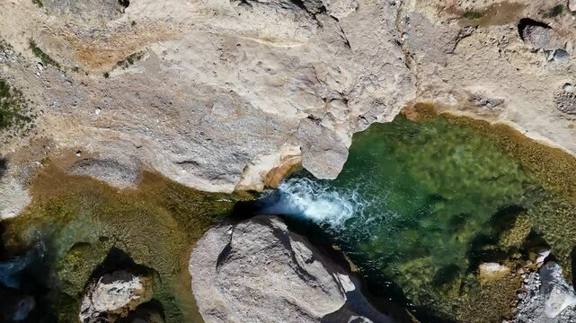 Aerial drone view of a ditail of a small waterfall on the Mula River, Murcia Region, Spain, with crystal-clear emerald waters.