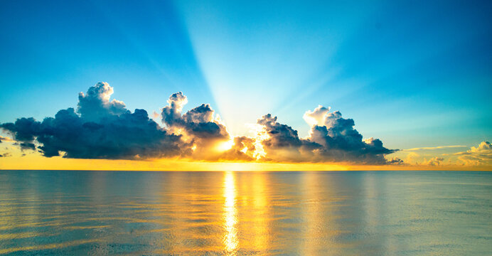 Sea sunset with cloudy sky and sun through the clouds over. Clouds Ocean and sky background, seascape.