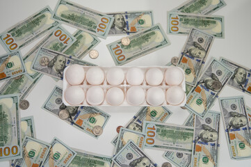 Chicken white eggs lie next to a stack of bills. Hundred-dollar bills are on the table with chicken eggs. Food inflation and the rise in price of chicken eggs