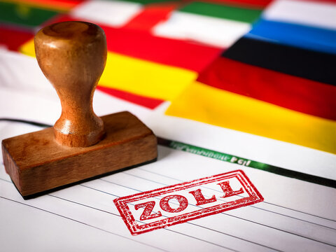 Ein zollamtlicher Stempel in Rot auf einem internationalen Frachtbrief, mit Flaggen verschiedener L&auml;nder im Hintergrund &ndash; symbolisiert Handelsbarrieren und globale Z&ouml;lle -Generated Image