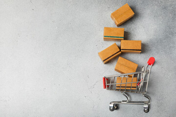 Online shopping concept.Cardboard box and shopping bags in a trolley on a bright colored...