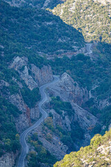 Winding road cuts through the rugged mountains of Parnon. Serpentine route carves into rocky cliffs...
