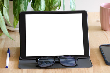 Fototapeta premium Digital tablet showing white screen on desk with coffee, pen, glasses and smartphone. tablet mockup