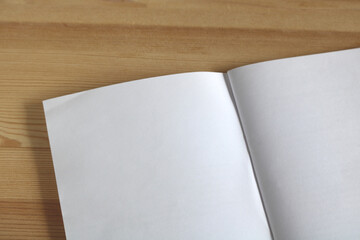Open notebook lying on wooden table with blank pages