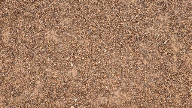 Brown small stone floor texture background. Rural roads or pavements are used for travel. Close-up aerial view of rough brown soil with no vegetation.