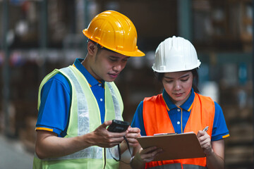 asian male and female worker checking storage. man and woman cargo support in workplace looking screen and write list board . male and female team inspect shelf stock safety protection like teamwork
