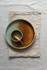 Round plate with a rim in a warm colors on a beige cotton tablecloth. Minimalistic composition with...