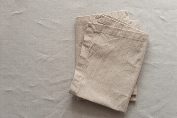 Сloth napkins in a warm colors on a beige cotton tablecloth. Minimalistic composition with natural elements in soft color palette. Crafted harmony concept