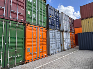 Group of cargo containers stacked in the terminal shipping yard area at the commercial port against the background of blue sky