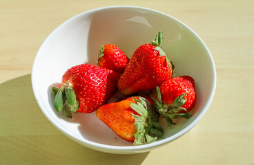 Fresh Strawberries Resting in a White Bowl on a Wooden Table