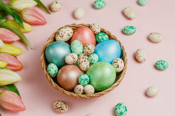 Easter eggsin basket on pink background with tulips.