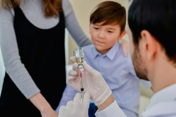 A healthcare professional prepares a vaccine while a child observes, highlighting the importance of...