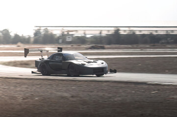 Gray-tuned sports car drifting on a racetrack during an intense time attack competition, showcasing...