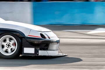 White sports car performing high-speed drift on racetrack, creating dramatic motion blur showcasing...