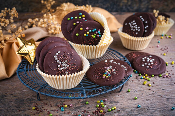 Artisan homemade fine dark chocolate thaler  decorated with colorful sugar pearls in muffin moulds