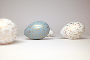 Stylish Easter eggs with golden patterns on white and pastel blue background. Minimalist composition with elegant decoration, perfect for spring and holiday themes.