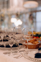 Close-up of an elegant wedding table setting with silver beaded chargers, white plates, dark napkins, and various wine glasses