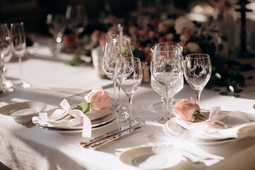 Elegant wedding table setting with a white tablecloth, white plates, light pink napkins, and...