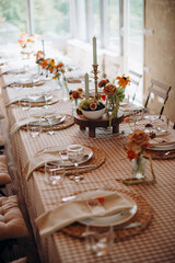 Elegant outdoor wedding table setting with a checkered tablecloth, woven placemats, simple floral...