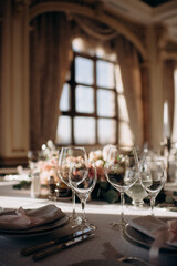 Elegant indoor wedding table setting with a white tablecloth, beige plates, tall wine glasses, and a silver candelabra with white candles