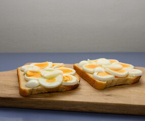 Two slices of toasted bread are topped with beautifully arranged boiled egg slices in a cozy kitchen setting, perfect for a nutritious breakfast