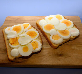 Two slices of toasted bread are topped with beautifully arranged boiled egg slices in a cozy kitchen setting, perfect for a nutritious breakfast