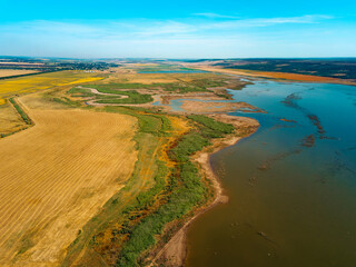 This aerial view showcases a vibrant landscape of vast farmland and a winding river flowing gracefully through