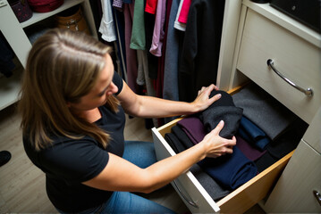 Woman Organizing Clothes in Closet Drawer for Neat Storage