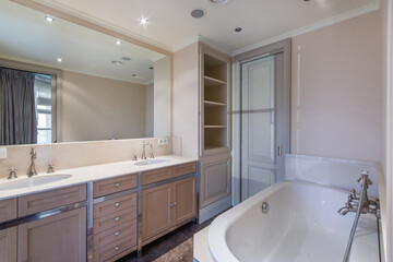 The bathroom is decorated in a classic style in warm pastel beige tones. Stylish faucets in retro style. Furniture with shelves and drawers.