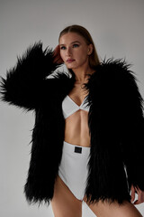 Fashion portrait of a woman in a black fur coat and white lingerie