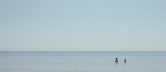 Ocean Horizon: Two figures, dwarfed by the immense sky, wade gently in the serene ocean, embracing the solitude and peace offered by the endless horizon. 