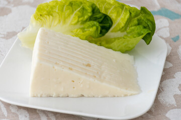 Spanish hard manchego, cow, sheep and goat cheese served for breakfast with green salad leaves close up