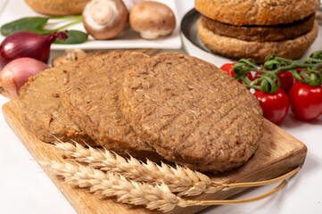 Round vegetarian patties or burgers made from grains, vital wheat gluten food, uncooked and grilled