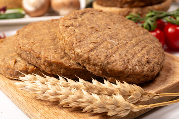 Round vegetarian patties or burgers made from grains, vital wheat gluten food, uncooked and grilled