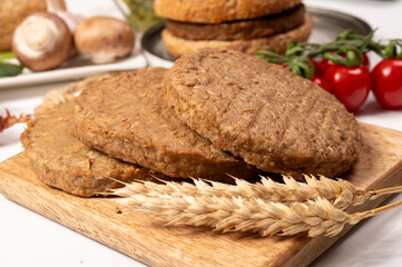 Round vegetarian patties or burgers made from grains, vital wheat gluten food, uncooked and grilled