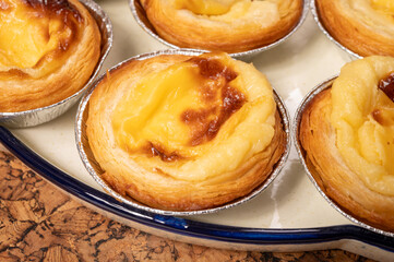 Portugal's traditional sweet dessert Pastel de nata egg custard tart pastry in cup close up on wooden background