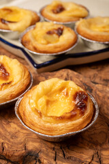 Portugal's traditional sweet dessert Pastel de nata egg custard tart pastry in cup close up on wooden background