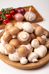 White and brown champignons mushrooms fresh uncooked on wooden plate copy space on white background