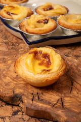 Portugal's traditional sweet dessert Pastel de nata egg custard tart pastry in cup close up on wooden background