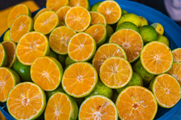 Close up of half cut green tangerines in a blue plastic basin, fruit backgrounds, Sri Lanka