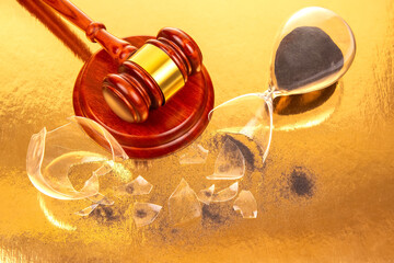 A finely crafted wooden gavel stands beside a fractured hourglass with black sand, photographed on...