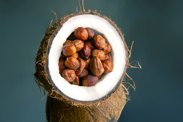 A coconut shell brimming with hazelnuts, captured on a dark background. Great for organic food...