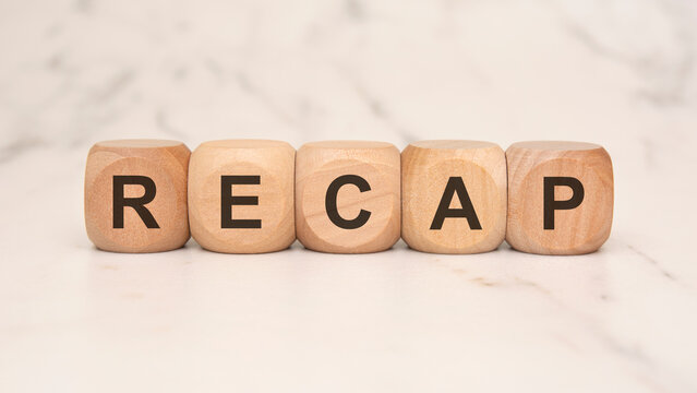 Wooden blocks spelling "RECAP" on a marble surface, symbolizing summaries or conclusions.