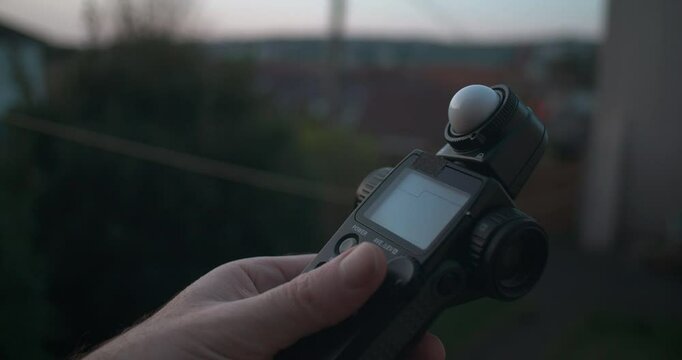 Photographer uses light meter to measure outdoor light levels