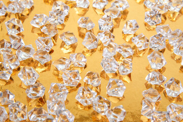 Shimmering clear crystals spread across a gold backdrop, showcasing their clarity and sparkle,...