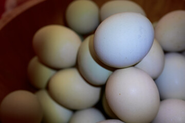 Fresh Farm Eggs in Natural Colors
A close-up of assorted fresh farm eggs in a wooden bowl, showcasing natural color variations from cream to light green.
