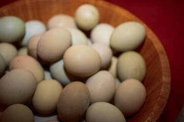 Fresh Farm Eggs in Natural Colors
A close-up of assorted fresh farm eggs in a wooden bowl, showcasing natural color variations from cream to light green.
