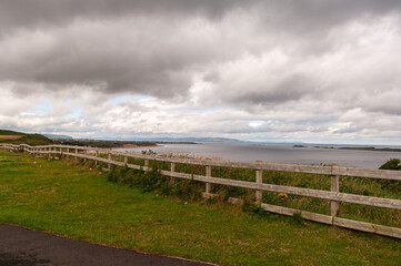Fototapeta premium A fence separates a grassy field from the ocean