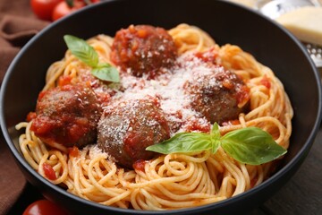 Delicious pasta with meatballs and cheese in bowl on wooden table, closeup